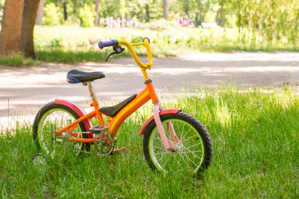 A red children bicycle is standing on the green grass