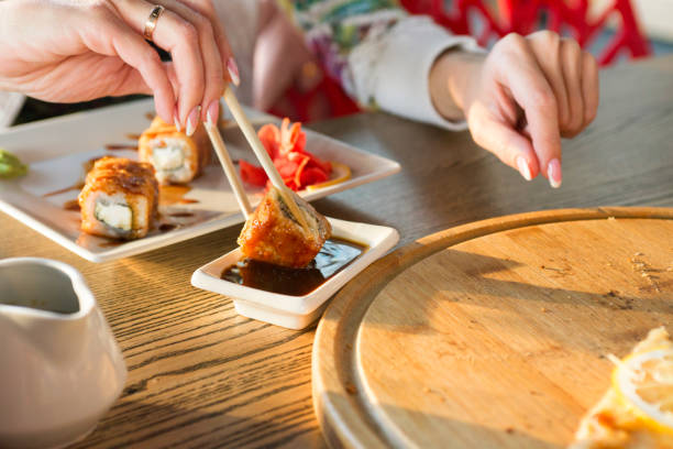 istock Young woman eating sushi roll in a restaurant 1280691016