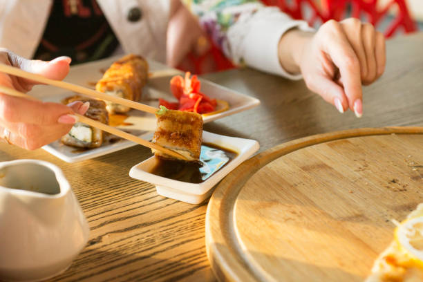 istock Young woman eating sushi roll in a restaurant 1280691024