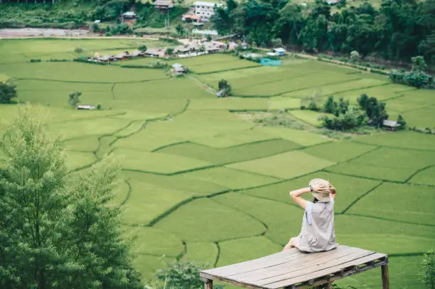 Photo of Rear view of tourist woman looking to beautiful rice paddy field in Sapan village of Nan province.