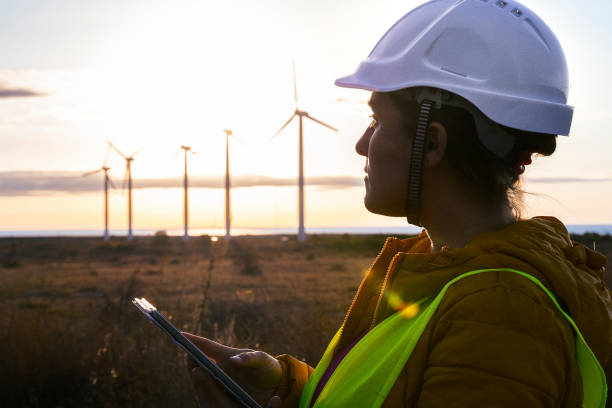 istock Renewable Energy Systems. Electricity Maintenance Engineer working on the field at a Wind Turbine Power station at sunrise. Girl power. 1280694939
