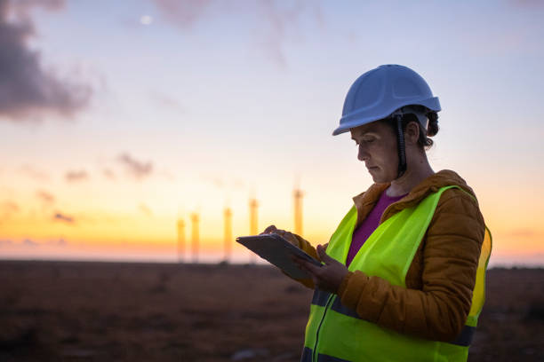 istock Renewable Energy Systems. Electricity Maintenance Engineer working on the field at a Wind Turbine Power station at dusk. 1280694950