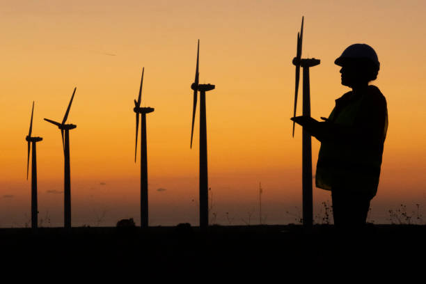 istock Renewable Energy Systems. Electricity Maintenance Engineer working on the field at a Wind Turbine Power station at dusk. 1280694965