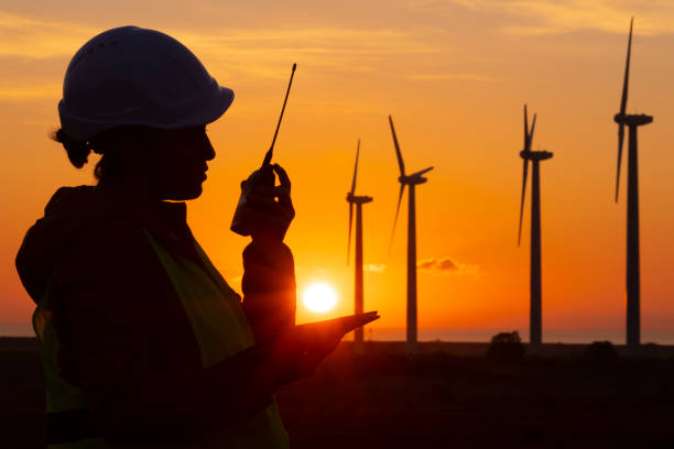 sistemas de energia renovável. engenheiro de manutenção de eletricidade trabalhando no campo em uma usina de turbinas eólicas ao anoitecer. falando com os colegas da rádio cb. - solar power station audio - fotografias e filmes do acervo