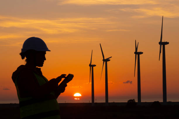 istock Renewable Energy Systems. Electricity Maintenance Engineer working on the field at a Wind Turbine Power station at dusk. 1280694970