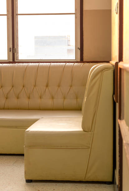 istock Old cream-colored sofa in the corner of the room with window light. 1280706030