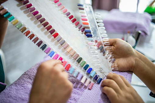 A set of fake nails for the customer to choose a color for a manicure or pedicure in a nail salon and spa store. Colorful artificial nails in a nail salon store. Sample palette of nail polishes.