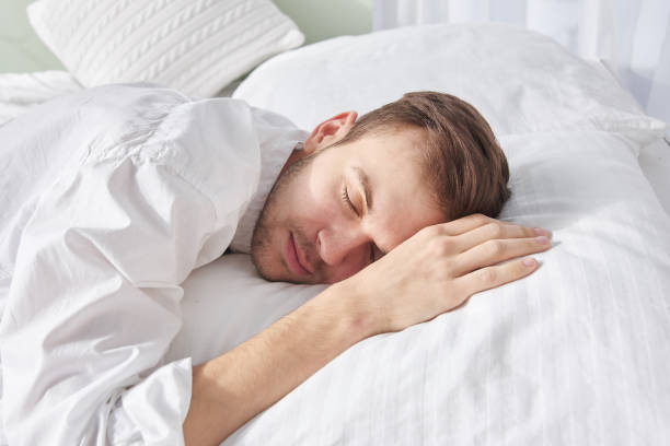 istock Close-up portrait of sleeping brunette man on white pillow 1280707583