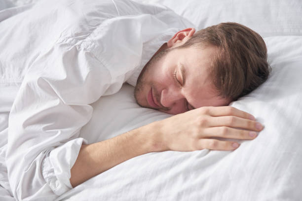 istock Close-up portrait of sleeping brunette man on white pillow 1280707587