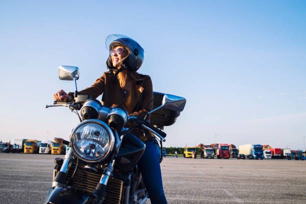 レトロなバイクに座って笑顔で革のジャケットとヘルメットを着た女性のオートバイ。 - motorcycle handlebar road riding ストックフォトと画像