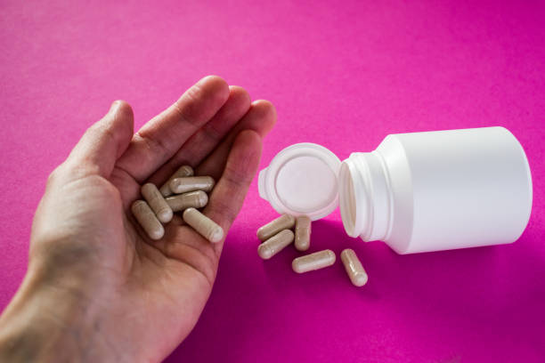 istock Hand holds white medical pills on pink background 1280712984
