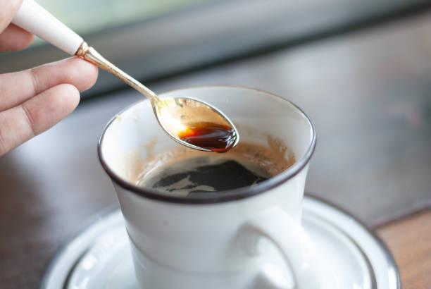 istock A hand holding silver spoon scooping some hot black coffee from a white ceramic mug, morning feel 1280717054