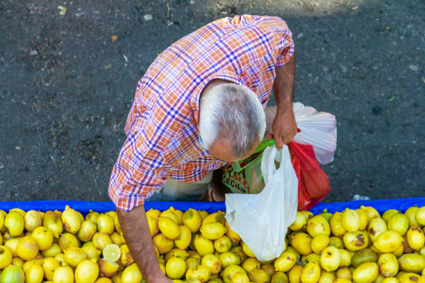 Esrefpasa Street, Izmir, Turkey- October 11, 2020: A man picks up and puts lemons in the plastic bag in Esrefpasa Bazaar, in Izmir, in Turkey.