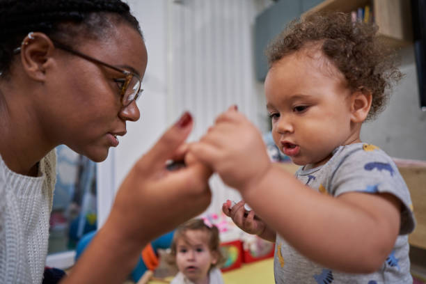 Lovely baby boy holding mother's hand while he learn how to make first steps