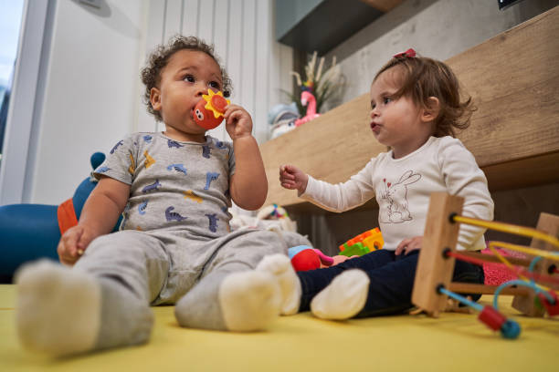 istock Mixed race baby boy biting a ruber toy while his female friend resents about that 1280720954