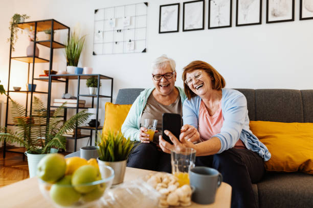 istock Senior women at home using smart phone and laughing while browsing through the selfie photos 1280724697