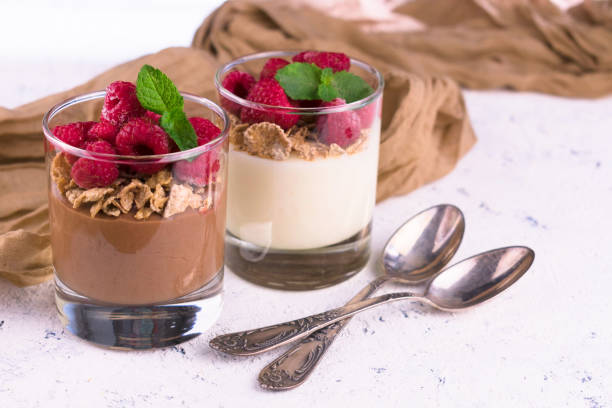 istock Two glasses with vanilla and chocolate pudding with raspberries and mint on the table. Close-up. 1280729162