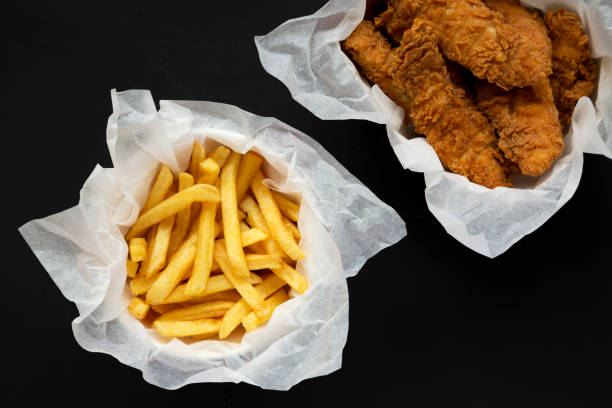 istock French Fries and Fried Chicken Strips on a black background, top view. Overhead, flat lay, from above. 1280731249