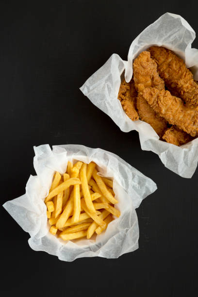 istock French Fries and Fried Chicken Strips on a black background, view from above. Overhead, flat lay, top view. Copy space. 1280731492