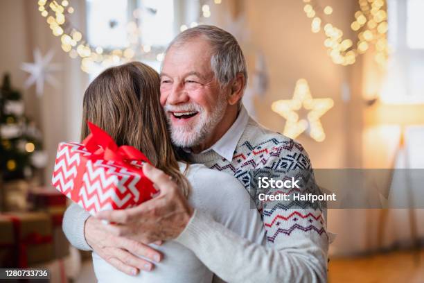 Young Woman Giving Present To Happy Grandfather Indoors At Home At Christmas Stock Photo - Download Image Now