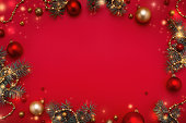 モミの木の花輪のクリスマスフレーム、赤いコピースペースの背景に金の装飾。
