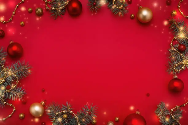 Red Christmas background. Fir tree frame, garland lights, gold decorations. Copy space, flat lay.