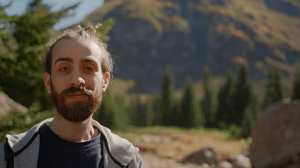 istock Naturalist long hair and bearded hipster man with backpack looking at camera and smiling, nature and lifestyle concept 1280741349