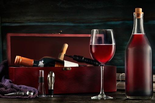 Low key image of red wine bottle and cup in a rustic nautical environment bar