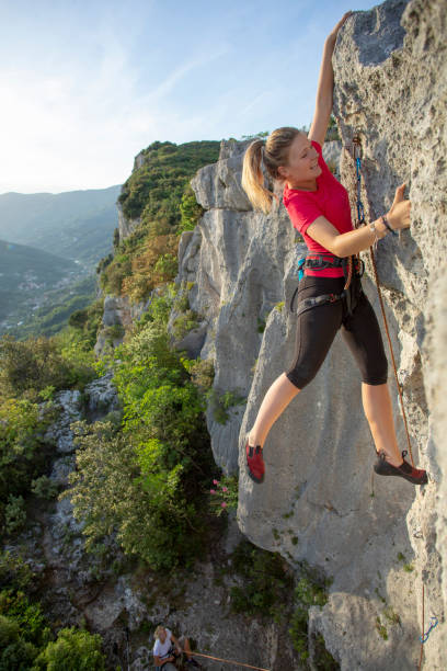 istock Young woman climbs vertical rock ridge 1280745735