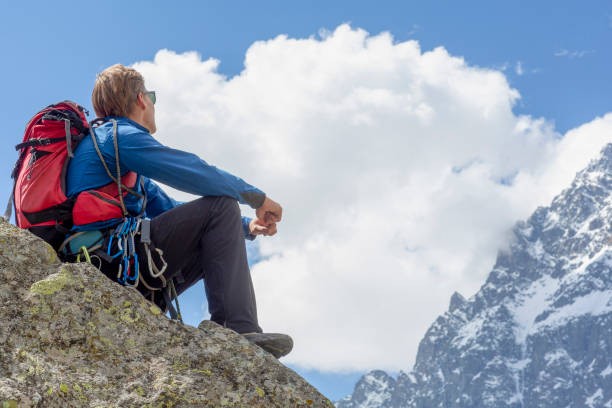 Mountaineer relaxes on mountain ridge