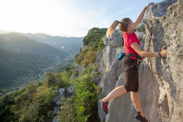 istock Young woman climbs vertical rock ridge 1280746357