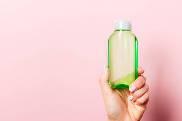 istock Pink background with woman's hand holding a cosmetics bottle with copy space 1280747096