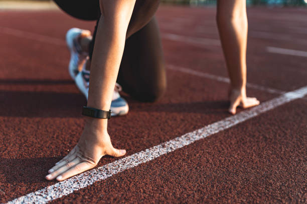 Female athlete on the starting line of a stadium track Woman athlete in starting position for running outdoors starting line stock pictures, royalty-free photos & images