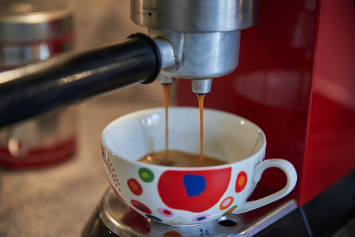 Brewing coffee with a coffee machine. Closeup of a coffee machine. Closeup of a colorful cappuccino cup. Making a cappuccino. Colorful cappuccino mug.