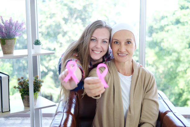 la figlia caucasica e la madre anziana in velo bianco sorride e tenere consapevolezza nastro rosa di cancro comune è il simbolo di varie attività della campagna per le pazienti con cancro al seno. - cancer chemotherapy drug baby family foto e immagini stock