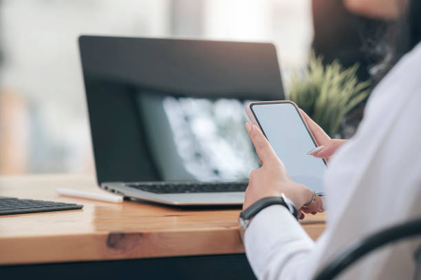 istock businesswoman using smartphone while sitting in front of laptop on the table in modern office. 1280750511