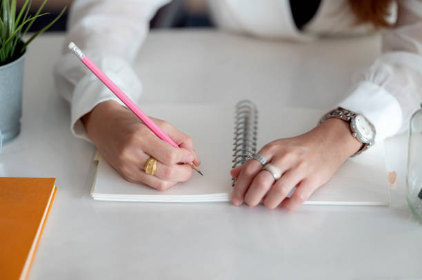 istock Cropped shot of female hand writing on blank notebook while working at office desk. 1280751885