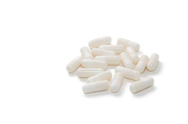 tiro de close-up de alto ângulo de pílulas brancas isoladas em fundo branco com espaço de cópia. conceitos de venda de produtos farmacêuticos e medicamentos. - capsule pill white nutritional supplement - fotografias e filmes do acervo