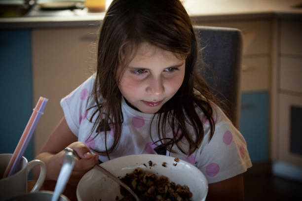 Little girl sitting watching digital tablet and eating