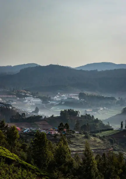 city view ooty from a hill top in early morning or dawn image taken at dawn form top angle. The image is showing the city nestled in the foothills of mountain.