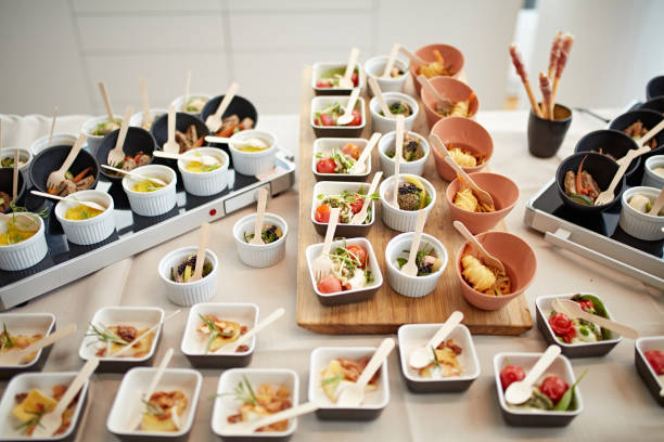 Variety of savory small dishes arranged on hot plates and cutting board covering buffet table for corporate event.