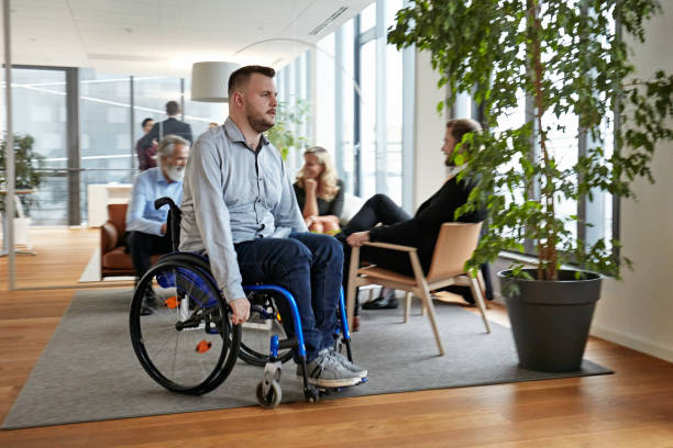 istock Young Businessman Rolling Through Office Lobby in Wheelchair 1280766966