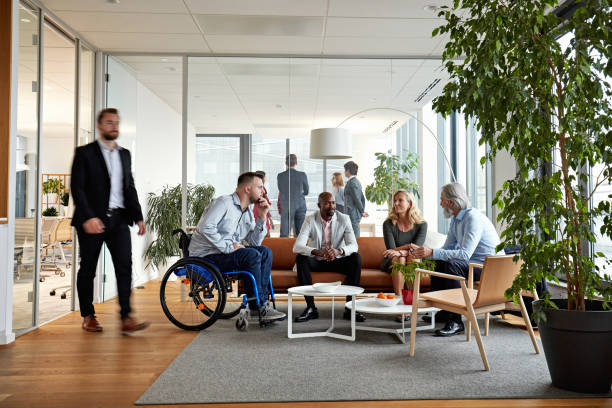 Diverse Executive Team Meeting in Office Reception Room Business associates in 20s, 40s, and 50s relaxing and exchanging ideas in sitting area of modern office. mixed age range stock pictures, royalty-free photos & images