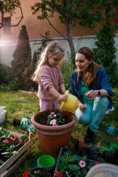 istock Three year old watering flowers with her mother 1280768179