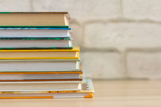 una pila de libros de tapa dura en una mesa o estante en la sala de la biblioteca. - childrens literature fotografías e imágenes de stock