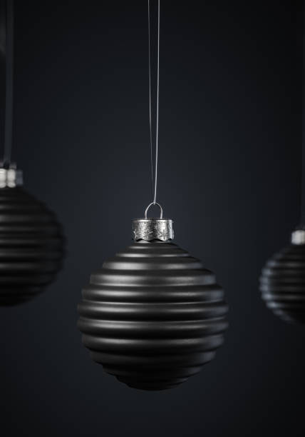 istock Three horizontally ribbed black Christmas balls hanging on strings against dark gray background. 1280771240