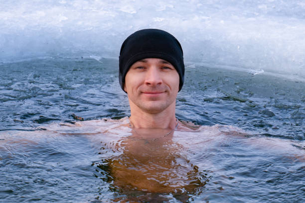 der kerl im hut ist winterschwimmen im kalten wasser. eislochtaufe - den sprung wagen fotos stock-fotos und bilder