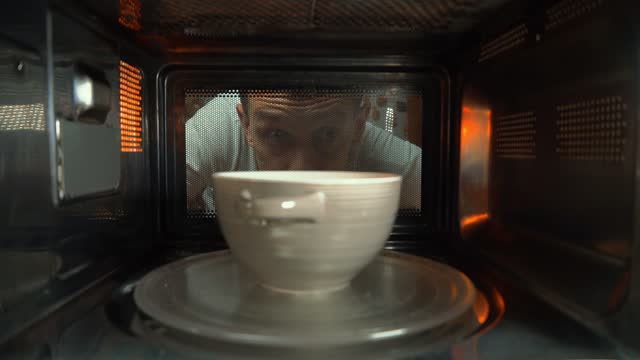 A ceramic bowl with some food is heated in the microwave, rotating