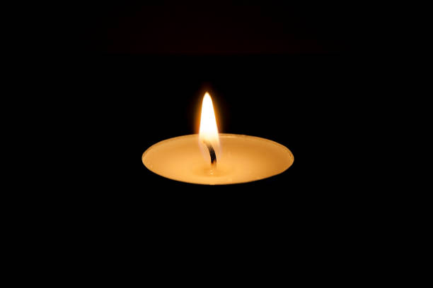 istock Closeup of a burning tea light with a dark black background. 1280777962