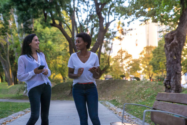 istock Two female walking around the park smiling 1280778038